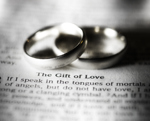 two rings rest by the words 'the gift of love'